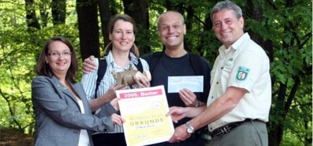 Bild 1: Die Norddeutschen Wildnis-Trail-Bezwinger Susanne Wiesemann und Dietmar Brede (Mitte) als 2.000ste Bucher des Wanderarrangements freuen sich über das Nationalpark-Schwein und einen Gutschein der Monschauer Klassik, überreicht von Cornelia Freuen,